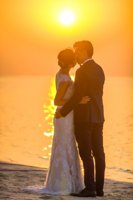 couple de mariés s'embrassant au coucher du soleil