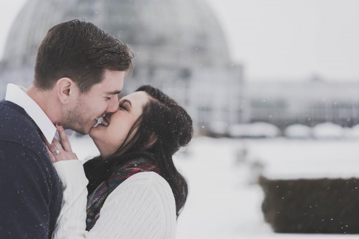 un couple qui s'embrasse sous la neige pour un mariage en hiver