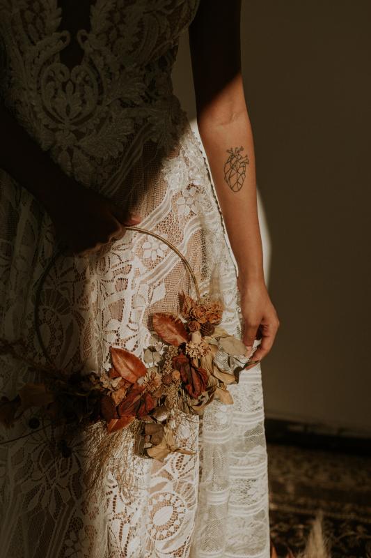 Mariage en Normandie - mariée dans sa robe de mariée vintage et ancienne blanche en dentelle tenant un cercle fleuri