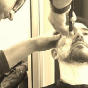 Photographie du coiffeur-visagiste qui rase une barbe d'un futur marié en Normandie  - Mariage en Normandie